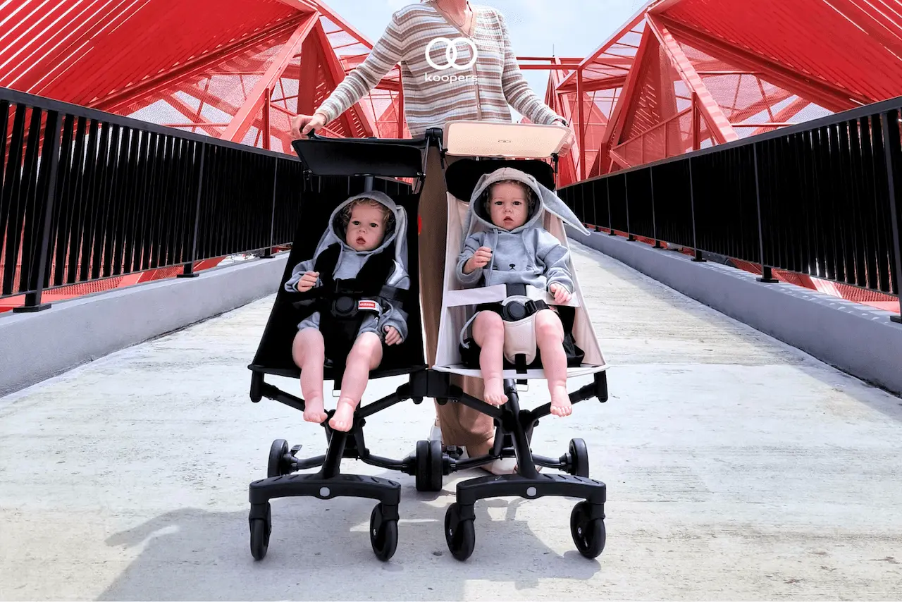 Two Koopers Aero travel strollers on a bridge in Malaysia, showcasing their lightweight and stylish design for modern families.