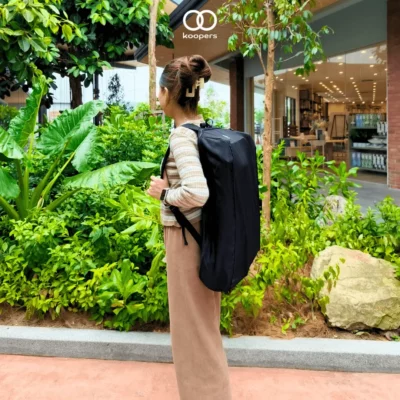 Side view of a woman carrying the Koopers Aero stroller in a compact backpack, ideal for travel in Malaysia.