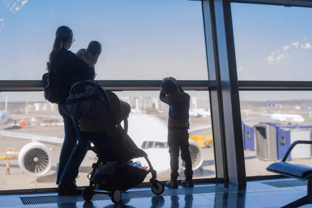 Family at the airport with the Koopers Aero stroller, highlighting its travel convenience and cabin-approved size in Malaysia.