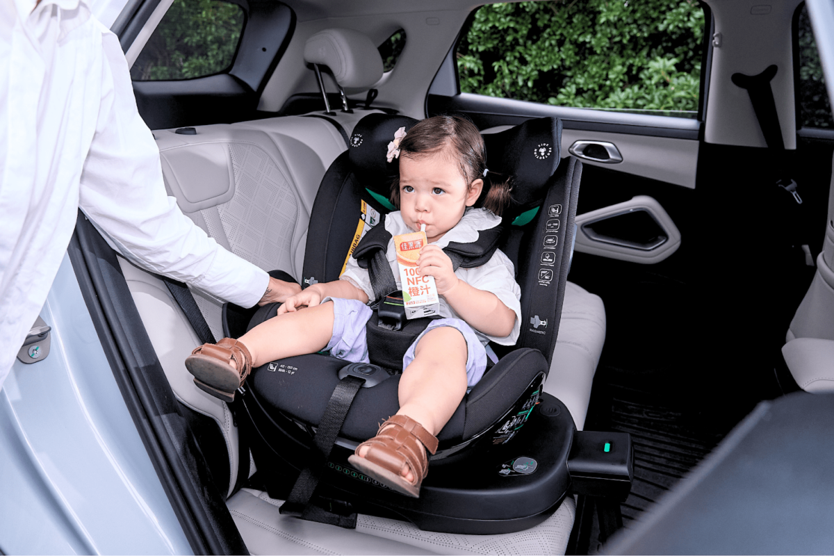 Child seated comfortably in the Koopers Armour 360 baby car seat during a car ride in Malaysia.