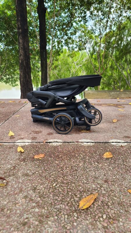 Folded Koopers Magic Rider 360 stroller placed on a path, highlighting its portability and practical storage.