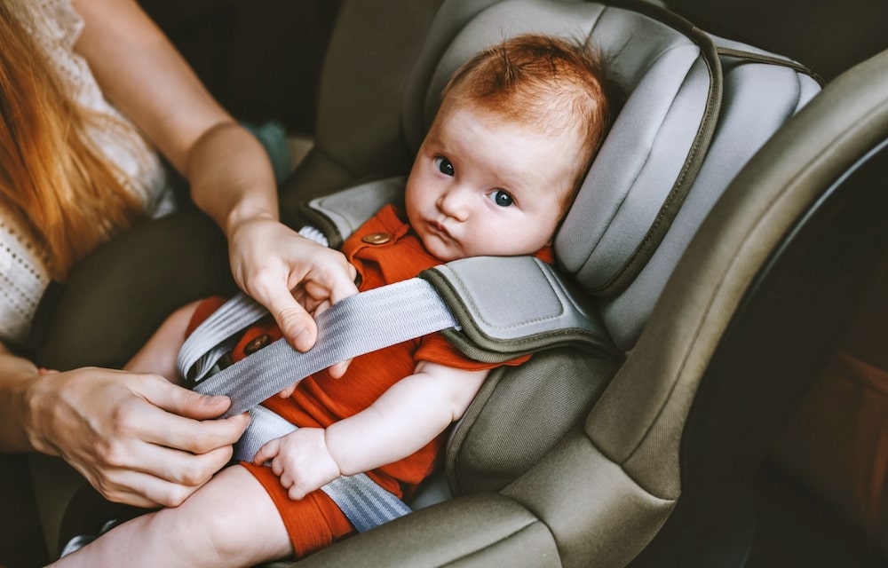understanding-baby-car-seat-installation-in-malaysia-step-by-step-guide-3 Mother adjusting the harness on a newborn baby car seat in Malaysia