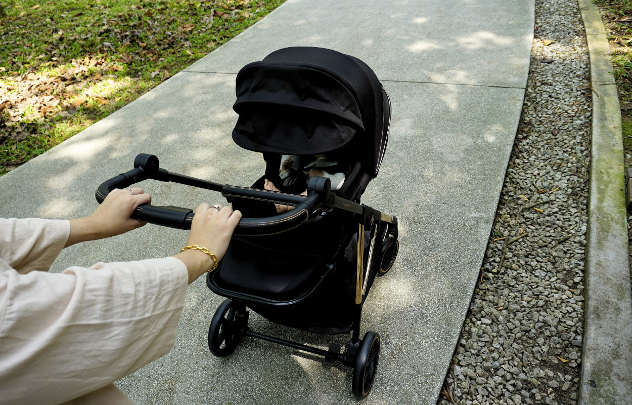 navigating-malaysian-terrain-with-the-right-baby-stroller-5 Parent pushing a baby stroller along a park pathway in Malaysia.
