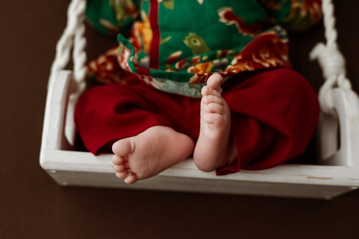 Close-up of baby feet on a baby swing, dressed in colorful traditional clothes, highlighting baby comfort at home