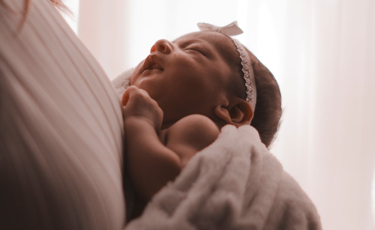 how-to-prepare-for-your-babys-first-year-2 Baby lying beside teddy bear on soft bedding – ideal for comfort and growth during the baby’s first year.