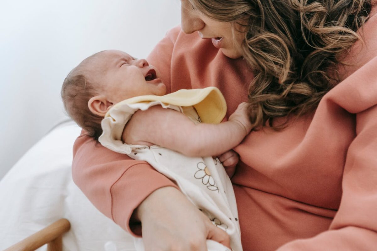 how-to-soothe-a-crying-baby-tips-that-actually-work-2 Newborn baby crying while held gently – highlighting common challenges of infant crying and need for soothing tools.