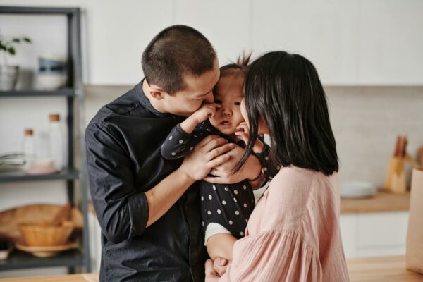 Top Features to Look for in a Baby Car Seat in Malaysia 2 Asian parents cuddling their baby at home, showing close family bonding and parental care