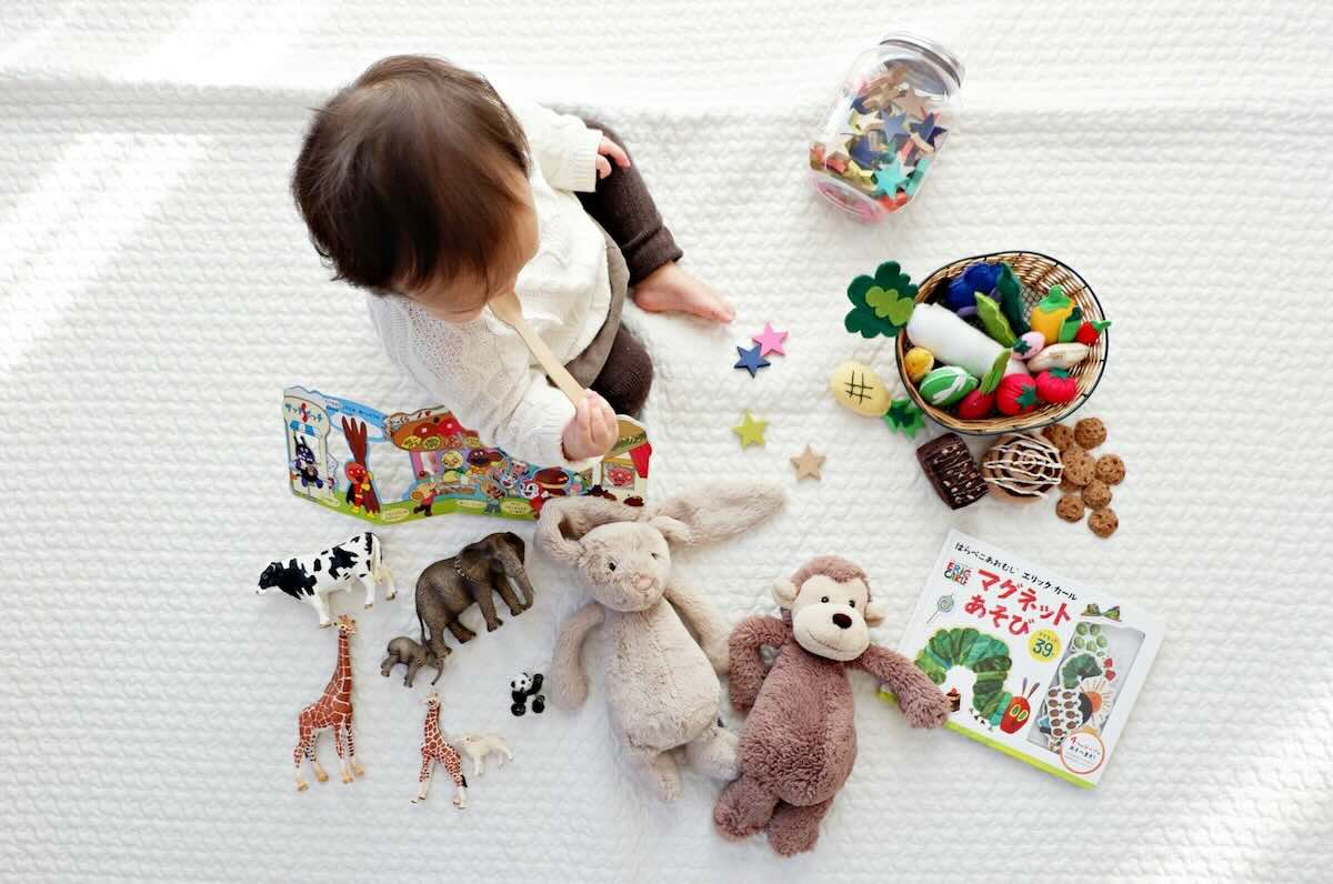 how-to-create-a-safe-sleep-space-with-a-playpen-baby-cot-in-small-rooms-1 Infant surrounded by soft toys, board books, and sensory items, playing safely on padded floor space in apartment