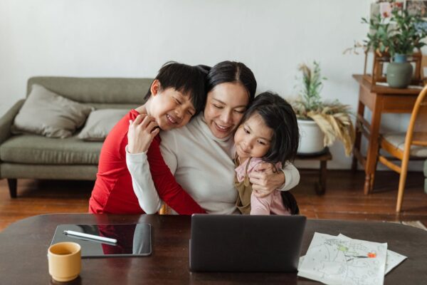 buying-baby-gear-online-vs-in-store-2 Smiling mother hugging her kids after completing online shopping on her laptop — showcasing work-from-home and family bonding in Malaysia.
