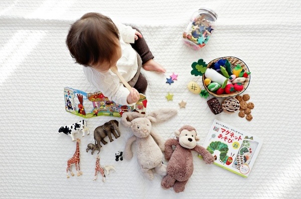 essential-daycare-car-seat-and-stroller-tips-6 Toddler surrounded by educational toys and books on a white mat, reflecting daycare learning and preparation.