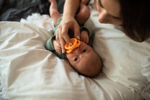 how-to-spot-fake-baby-car-seat-in-malaysia-1 Newborn lying on bed with pacifier — importance of certified baby gear
