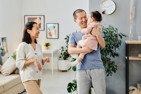 why-you-should-always-test-fit-baby-gear-before-buying-7 Parents playing with their toddler in a modern living room, highlighting safe home use of baby gear like cots and strollers.
