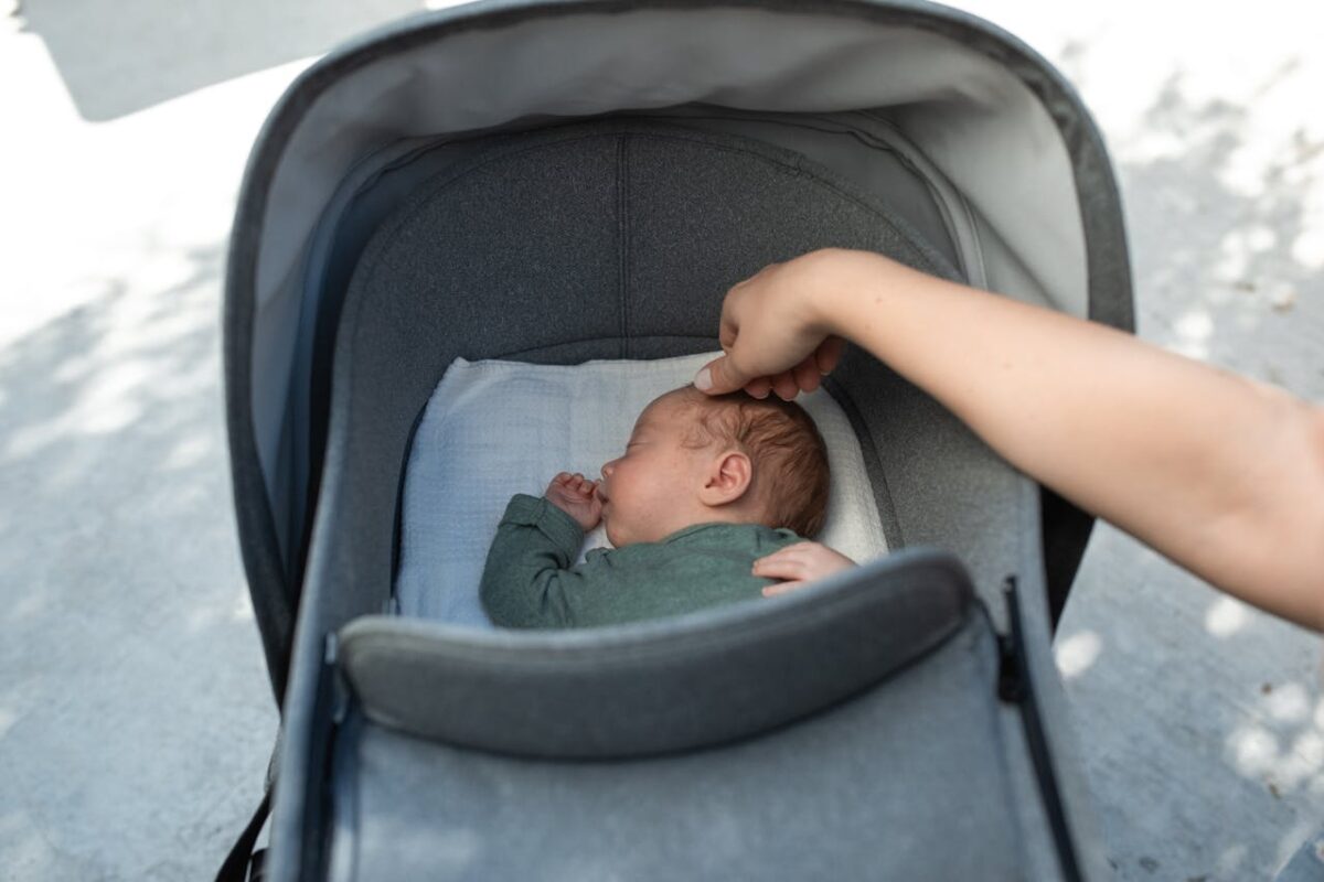 Parent soothing a baby sleeping comfortably in a stroller bassinet.