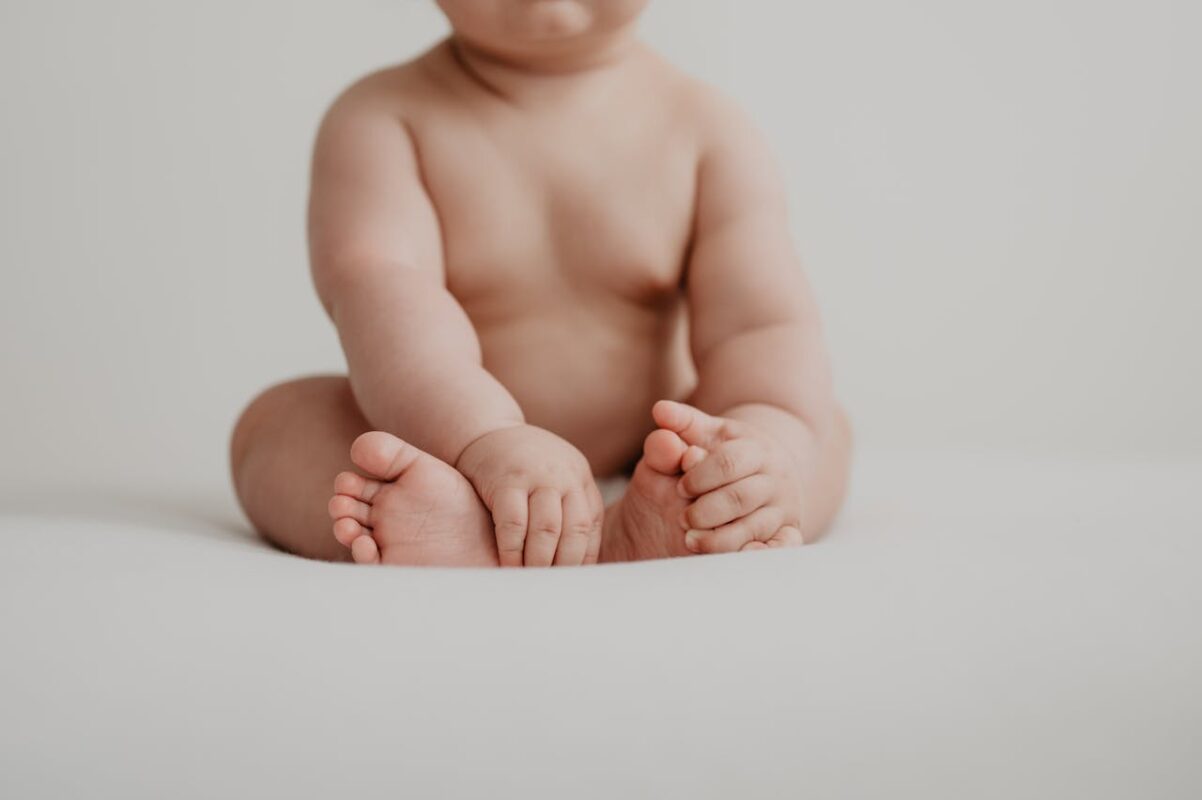 how-to-keep-baby-cool-in-stroller-malaysia-1 Close-up of baby sitting indoors showing chubby legs and feet, representing baby comfort in Malaysia’s heat