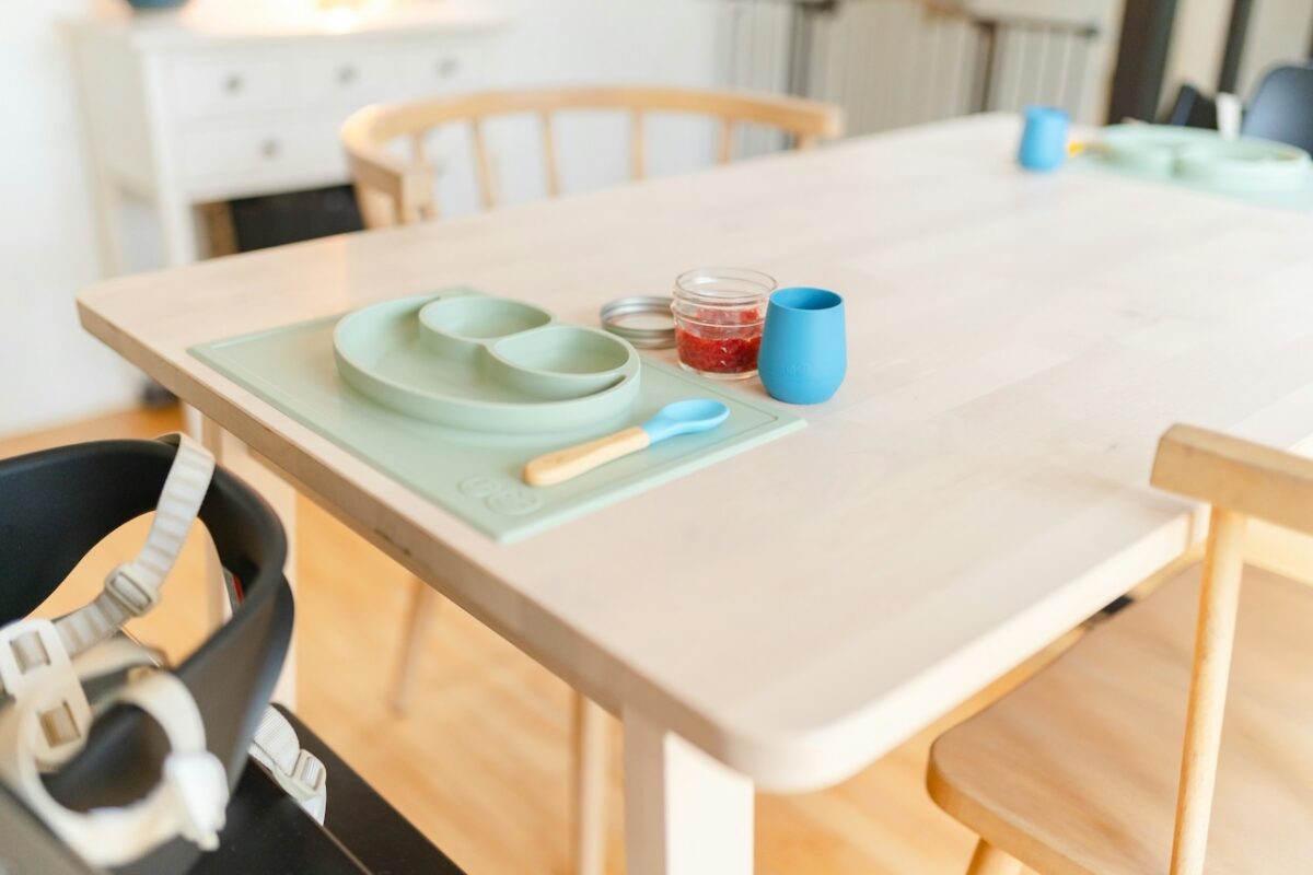 baby-high-chairs-building-healthy-mealtime-routines-1 Baby high chair positioned at a dining table, with feeding tray, utensils, and baby meal setup ready.