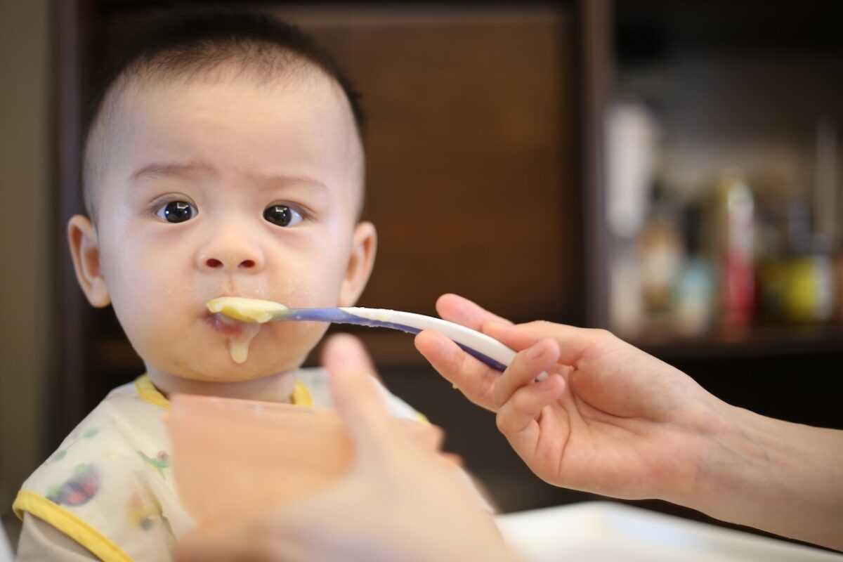 baby-high-chairs-building-healthy-mealtime-routines-3 Close-up of a baby being fed in a high chair, supported upright during early solid food feeding.
