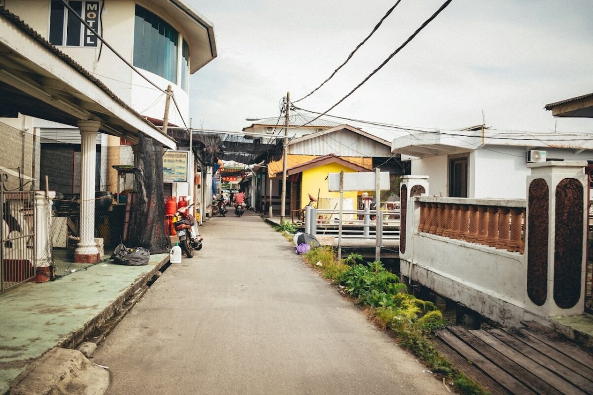 balik-kampung-with-baby-tips-for–parents-20 Narrow kampung street with colorful Malaysian village houses on stilts for balik kampung Raya, uneven paths ideal for jogger stroller and cabin stroller Malaysia family travel.