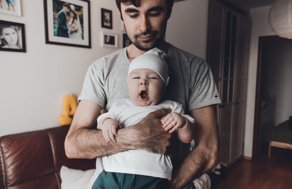 building-strong-bonds-with-your-newborn-daily-8 Loving Malaysian dad holding yawning newborn baby for strong bonding moment, using Koopers 360 car seat and baby jogger stroller for active family play.