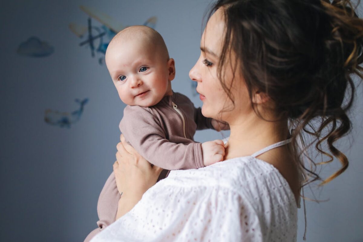 Loving Malaysian mum holding smiling newborn baby for skin-to-skin bonding in nursery, building secure attachment daily with Koopers baby gear